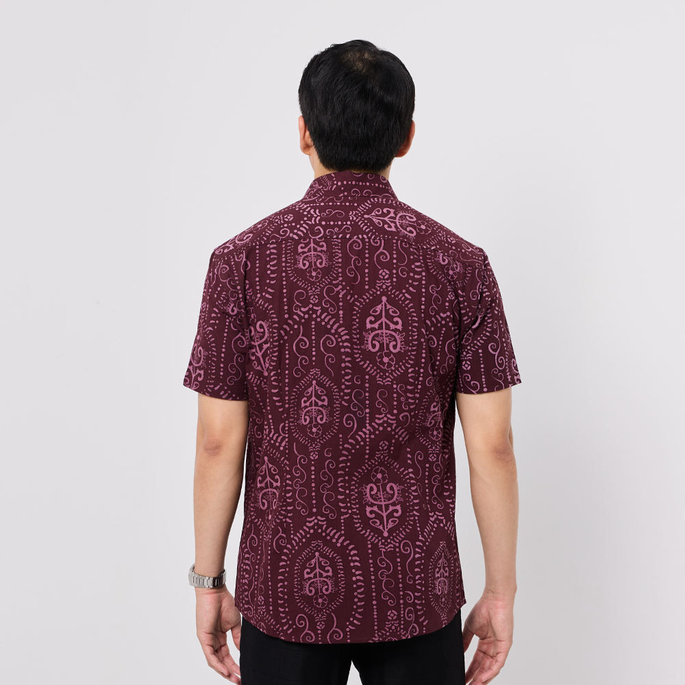Person wearing a maroon patterned shirt on a white background
