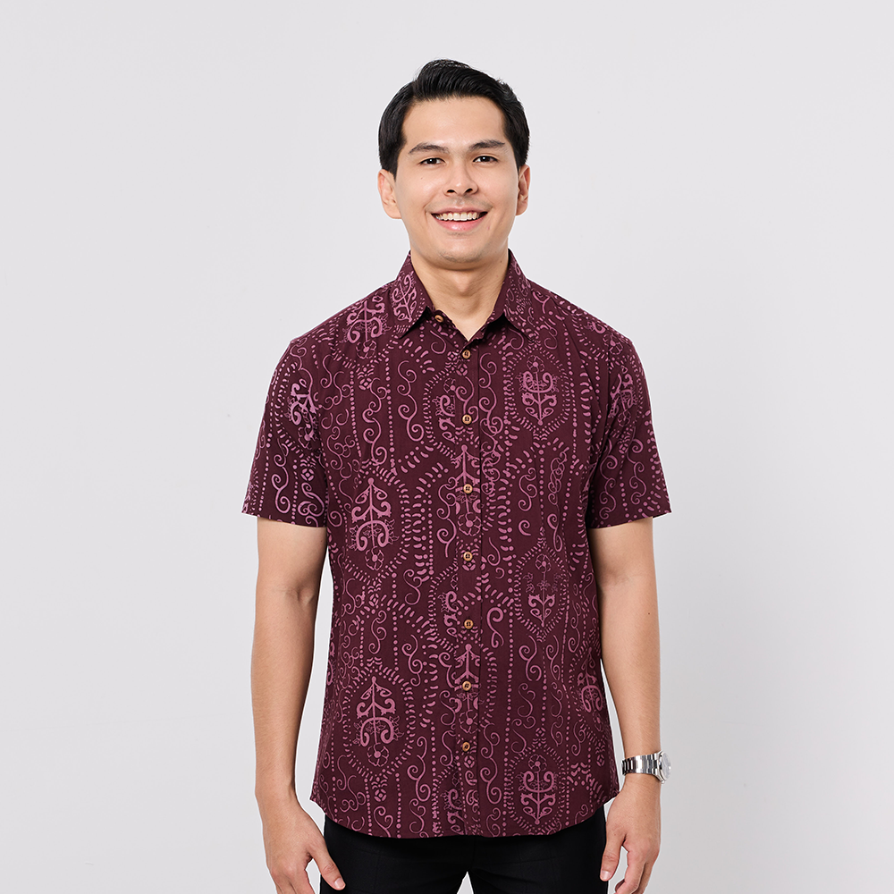 Man wearing a patterned maroon shirt on a light gray background