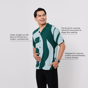 Man wearing a green and white patterned shirt on a light gray background