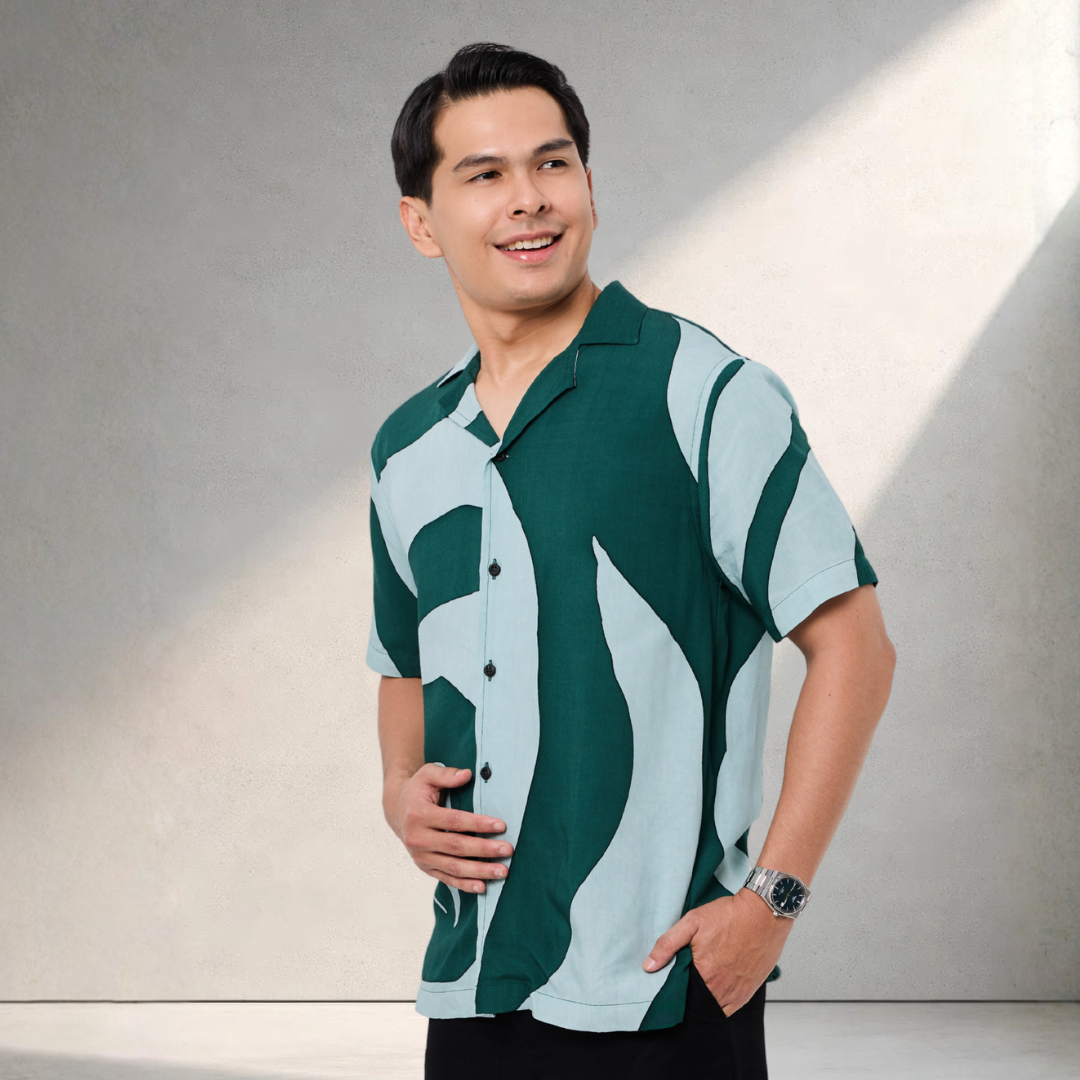 Man wearing a green and light blue patterned shirt against a neutral background