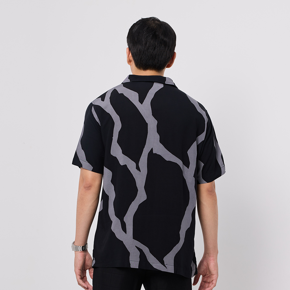 Person wearing a black shirt with gray abstract pattern on a white background
