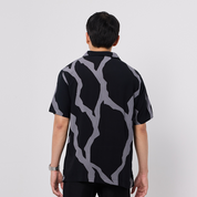 Person wearing a black shirt with gray abstract pattern on a white background