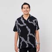 Man wearing a black and gray patterned shirt on a white background