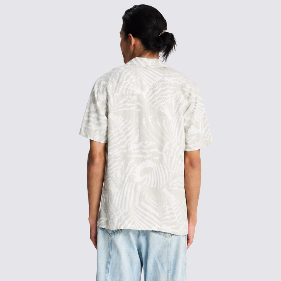 Man facing the back showing the back print of the gray batik shirt he's wearing