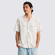 Man wearing gray printed batik shirt, facing the front with hands in his pockets