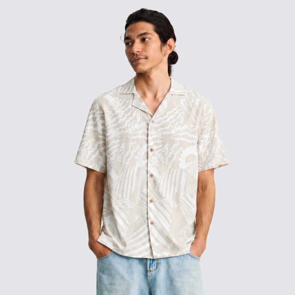 Man wearing gray printed batik shirt, facing the front with hands in his pockets