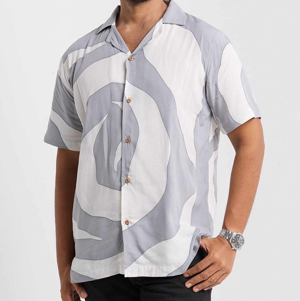 Man wearing a patterned shirt with abstract design on a plain background