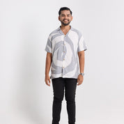 Man wearing a patterned shirt and black pants on a white background