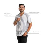Man wearing grey printed batik shirt, posing with his hand by the buttons and annotated features by the sides
