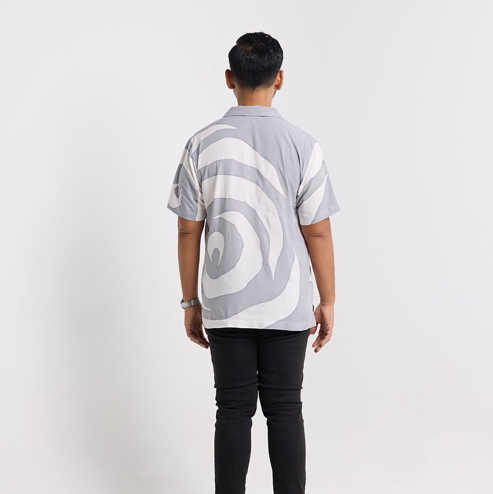Person wearing a gray and white patterned shirt on a plain background