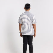 Person wearing a gray and white patterned shirt on a plain background