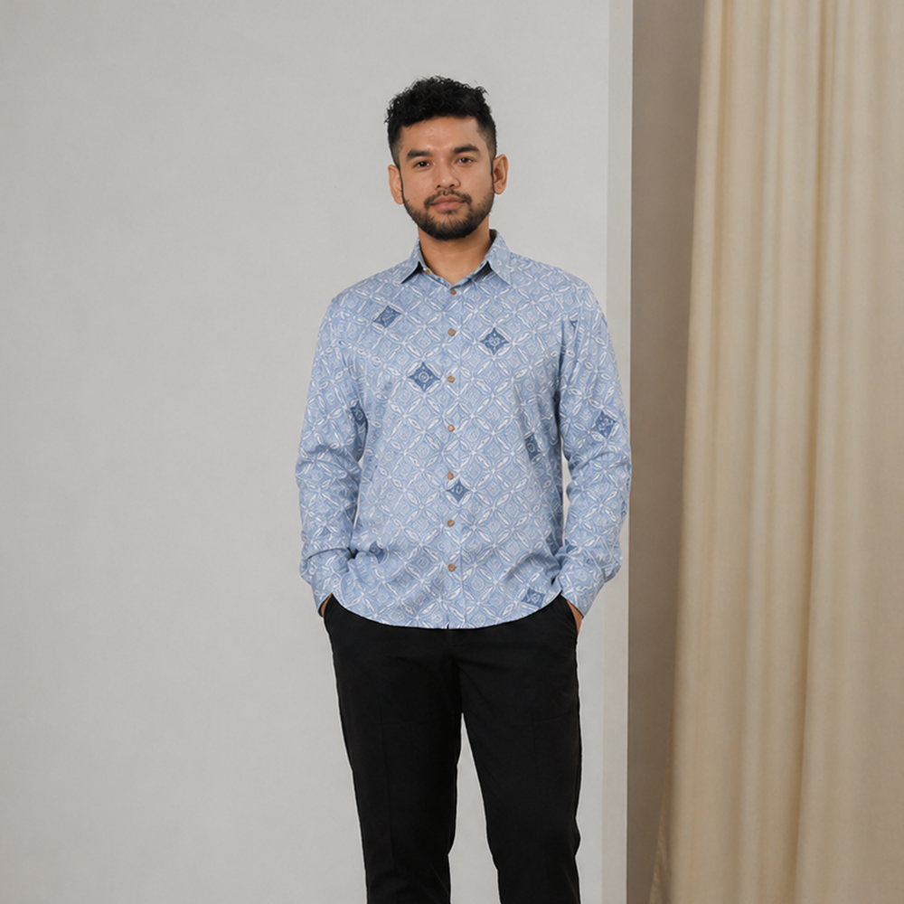 Man wearing a blue patterned shirt and black pants against a neutral background