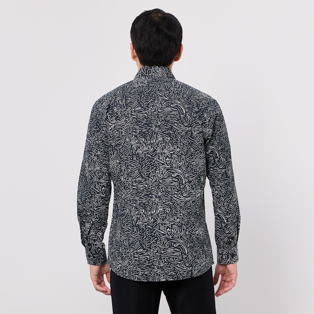 Person wearing a black and white patterned shirt on a plain background