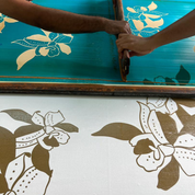 Person using a screen printing tool on fabric with floral designs.