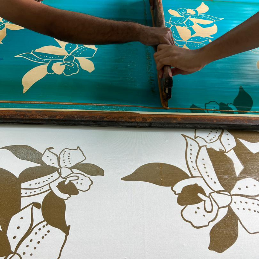 Person using a screen printing tool on fabric with floral designs.