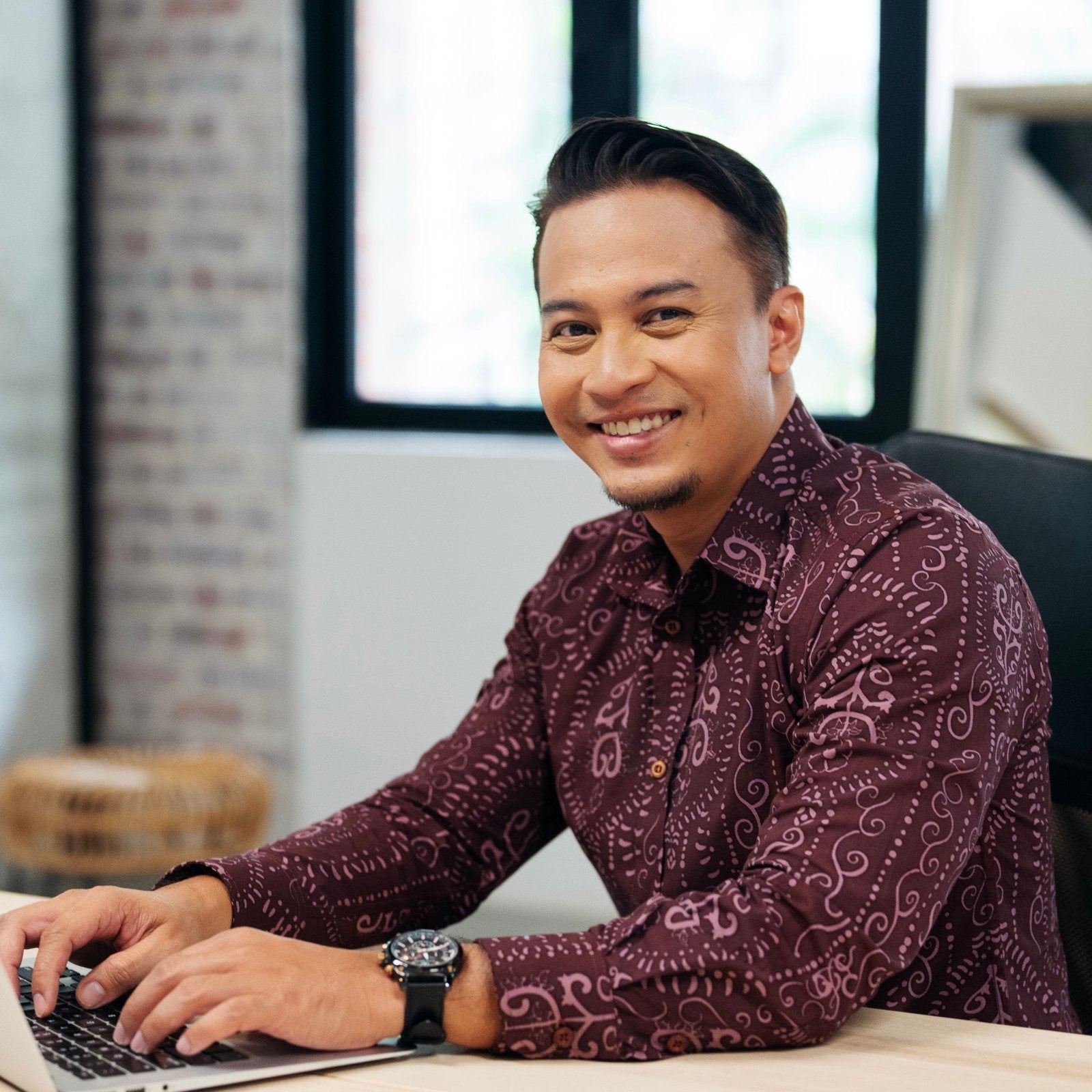 man wearing the Men's Long-Sleeved Batik Shirt Garnet Petola showing it being worn in a workplace lifestyle photo 