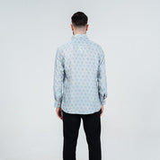 Man wearing a light blue patterned shirt and black pants on a white background