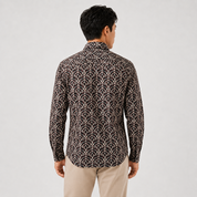 Man wearing a patterned shirt and beige pants on a light gray background