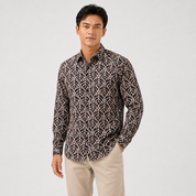 Man wearing a patterned shirt and beige pants on a white background