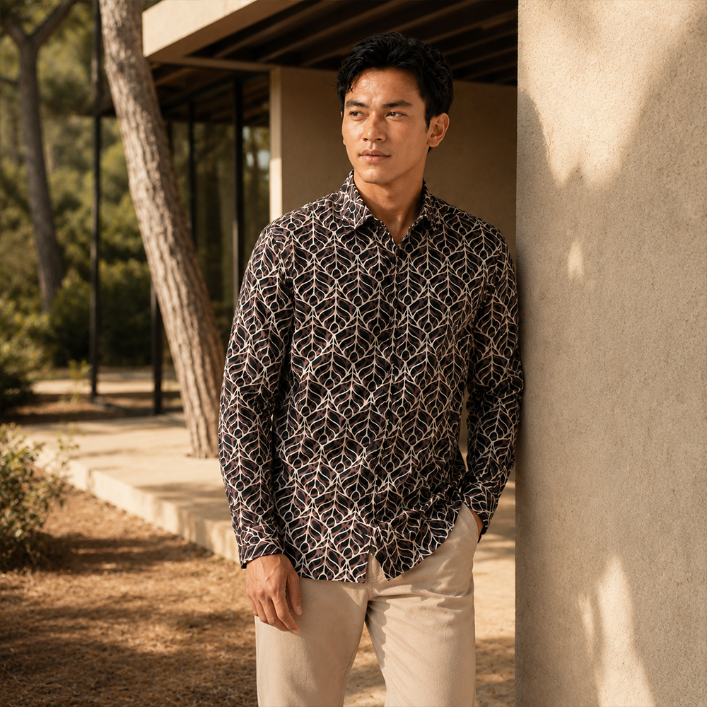 Man wearing a patterned shirt and beige pants leaning against a building.
