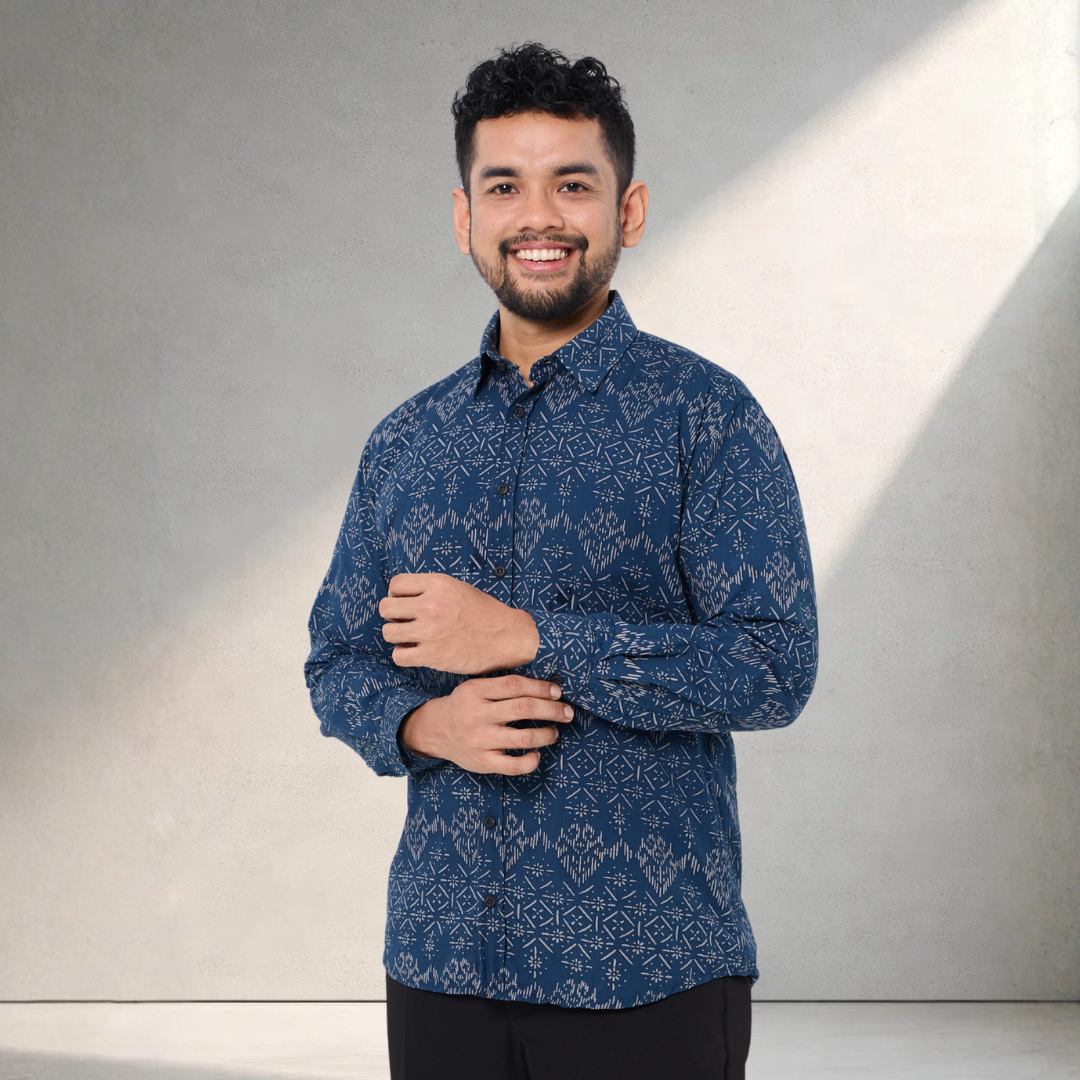 Man wearing a blue patterned shirt against a neutral background