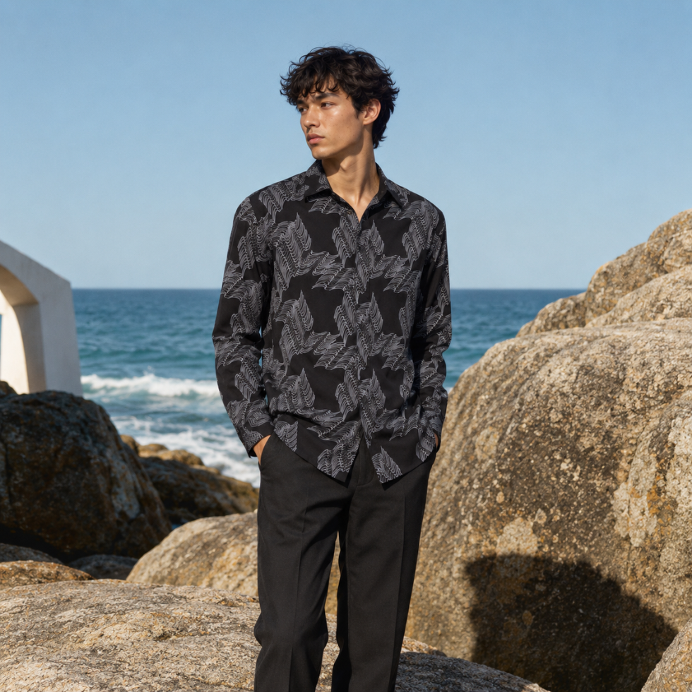 Man posing wearing black printed batik shirt b the beach