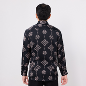Person wearing a black patterned shirt on a white background