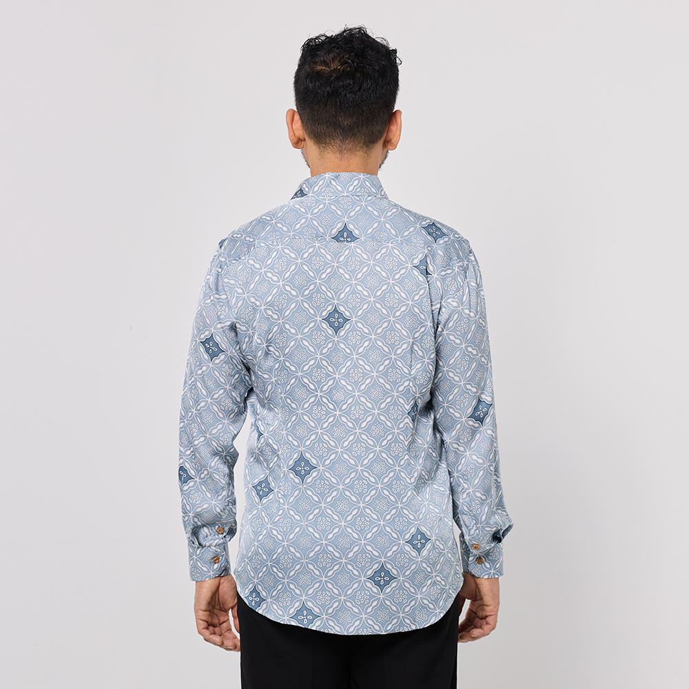 Man wearing a light blue patterned shirt on a plain background