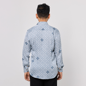 Man wearing a light blue patterned shirt on a plain background