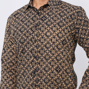 A close-up of a men's long-sleeve button-up shirt featuring an intricate geometric and floral block-print pattern in beige on a black background.