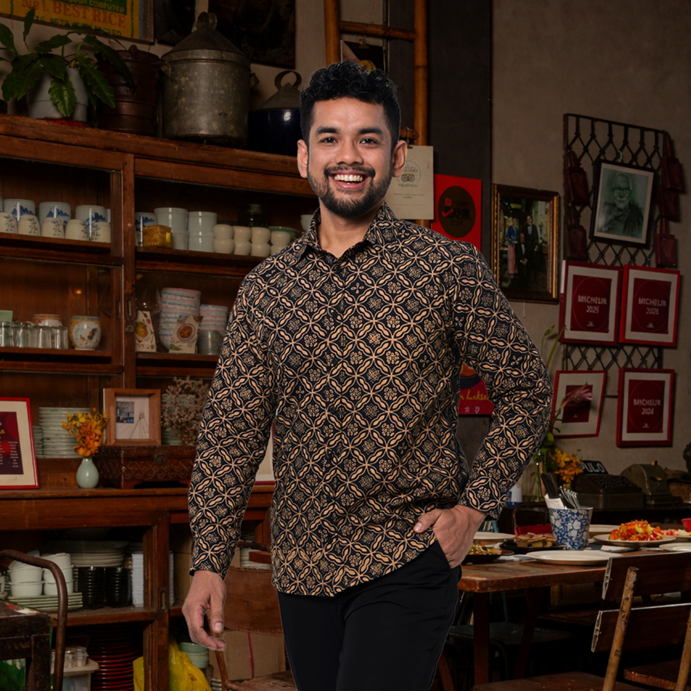 Man standing in a room with wooden shelves and framed pictures on the wall.