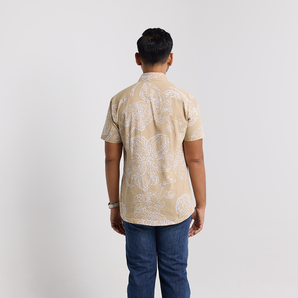Person wearing a beige patterned shirt and blue jeans on a white background
