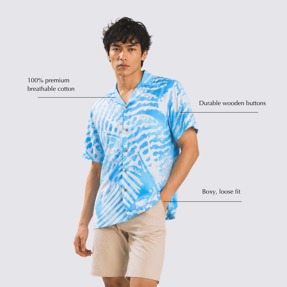 Man wearing light blue printed batik shirt with shell-like prints posing with hand in his pocket and annotated details by his sides