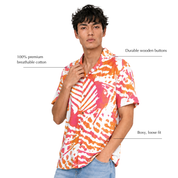 A man modeling a short-sleeve button-up shirt with a bold orange, pink, and white abstract pattern. The image includes text callouts highlighting features like '100% premium breathable cotton', 'Durable Wooden buttons', and 'Boxy, loose fit'.
