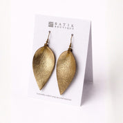 Gold leaf-shaped earrings on a Batik Boutique card against a white background