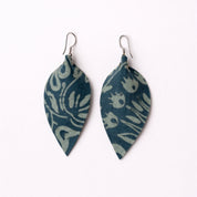 Pair of blue patterned leaf-shaped earrings on a white background