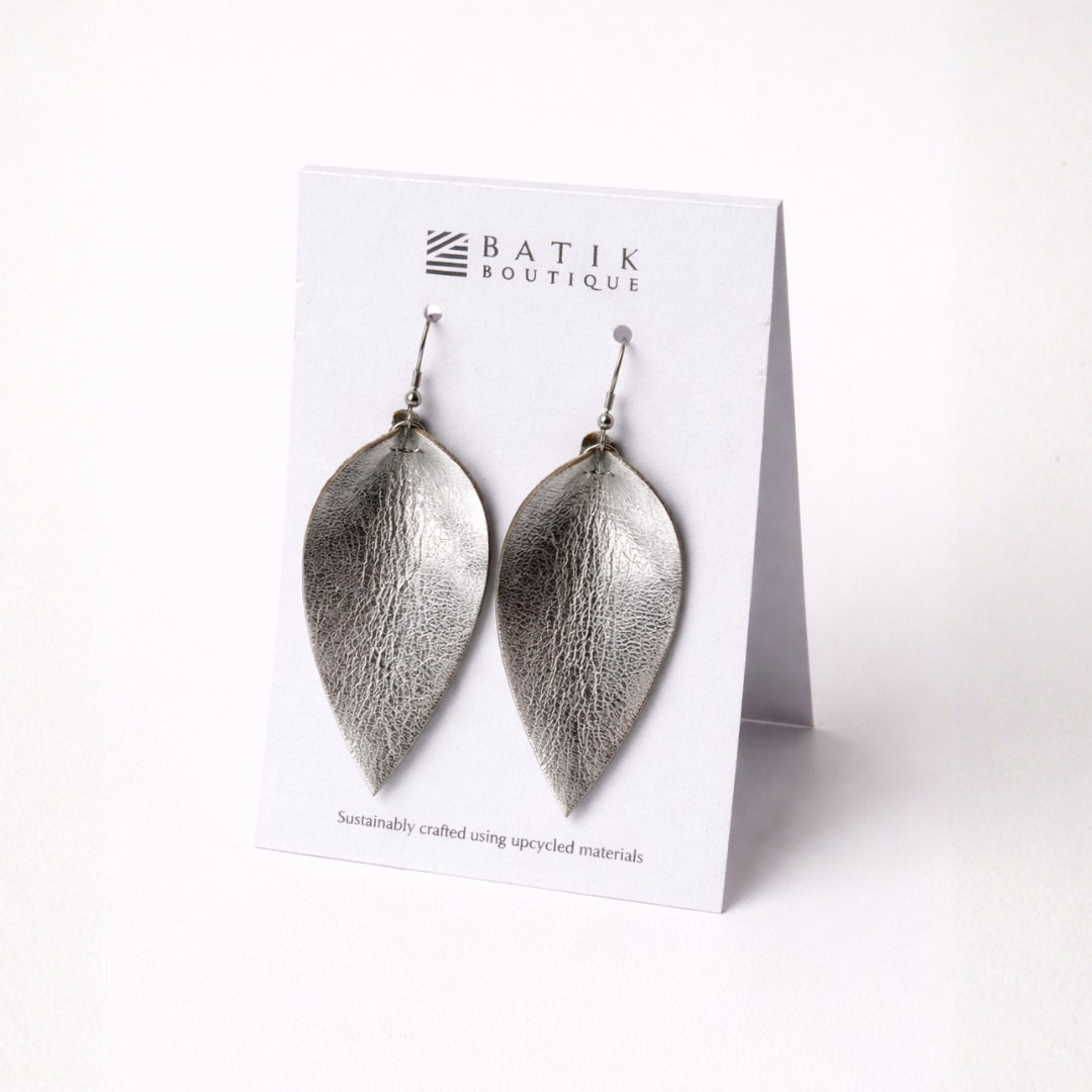 Silver leaf-shaped earrings on a Batik Boutique card against a white background