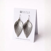 Silver leaf-shaped earrings on a Batik Boutique card against a white background