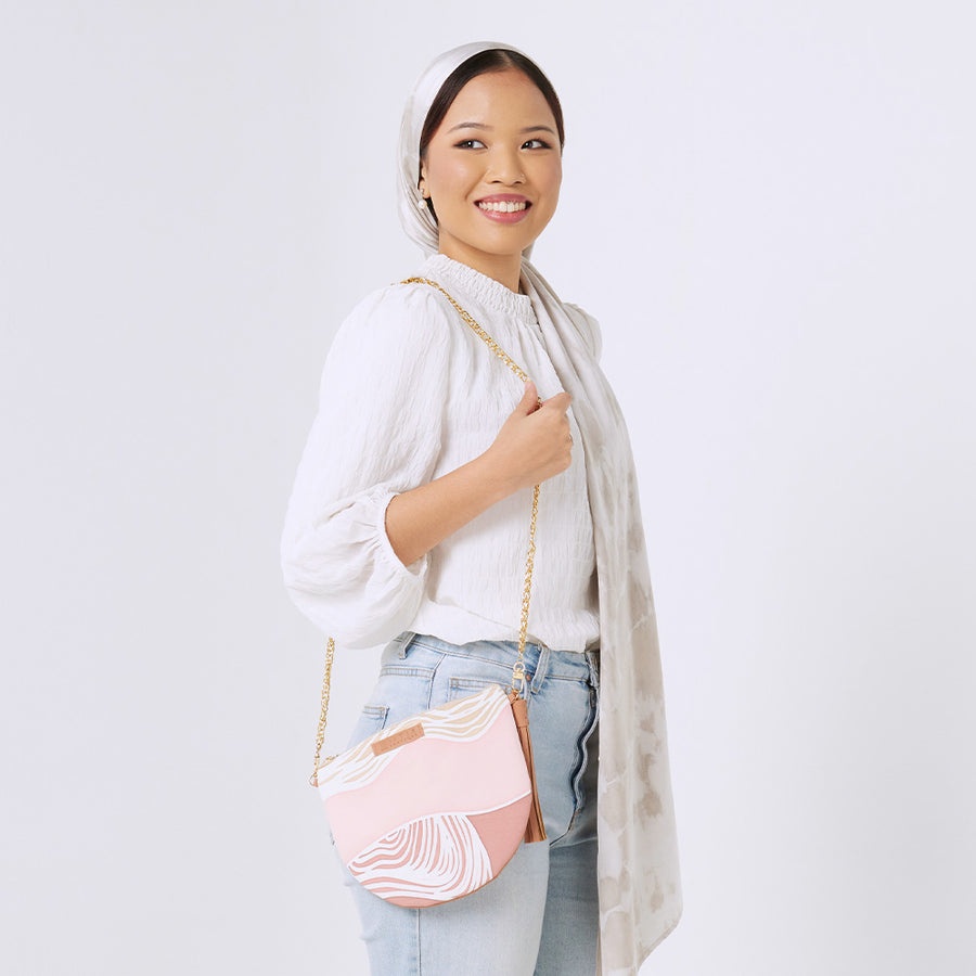  a woman standing in front of white background styling batik Moon Clutch Bag in Dawn Bukit pattern