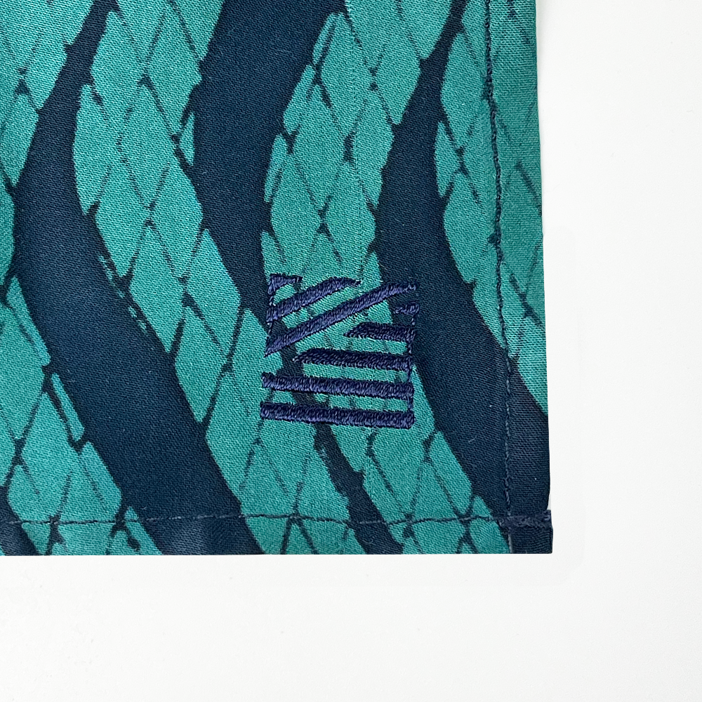 a closeup of embroidery against a white background in the pattern teal snakeskin