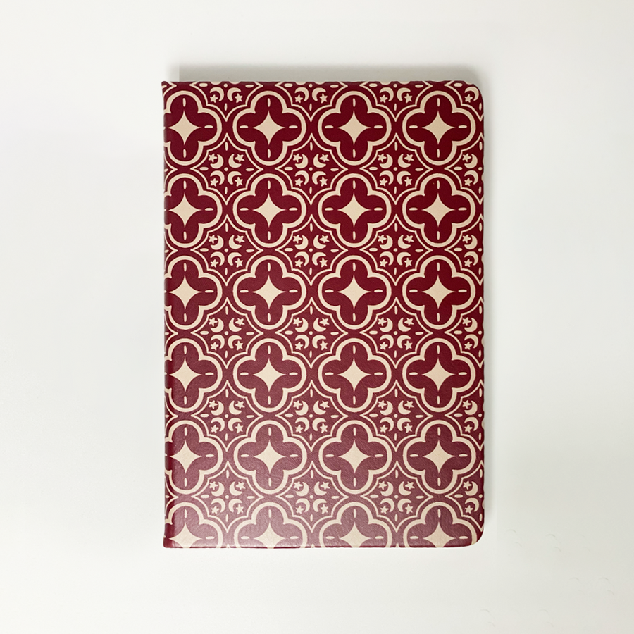 A photo showing batik-inspired leather notebook in crimson celestial print