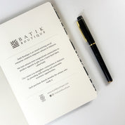 Batik-Inspired Notebook & Pen - Black Floret note book opened and showing the first page with a pen that comes along with the set 