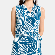 A sleeveless wrap-style dress with a bold blue and white abstract pattern, featuring a V-neckline and side tie detail, shown on a model against a light gray background.