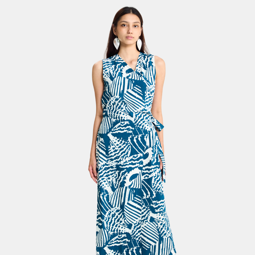 A sleeveless wrap-style maxi dress with a bold blue and white abstract pattern, worn by a model against a light gray studio background.