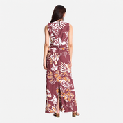 A woman viewed from the back wearing a sleeveless midi dress with a white and light maroon abstract pattern and a matching tie belt at the waist, set against a plain light gray studio background.