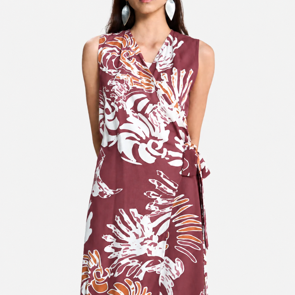 A sleeveless wrap-style dress with a V-neckline and self-tie waist, featuring an abstract white and light maroon pattern, shown on a model against a light gray background.