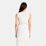 A woman viewed from the back wearing a sleeveless midi dress with a white and light gray abstract pattern and a matching tie belt at the waist, set against a plain light gray studio background.