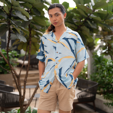 a male model posing in a batik shirt in the pattern ocean palma against a tropical greeneries in a lifestyle photo