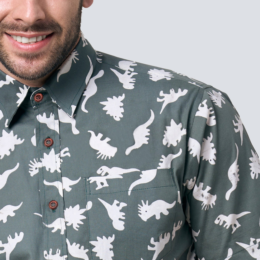 a close-up of a man wearing a batik shirt in olive dinosaur pattern