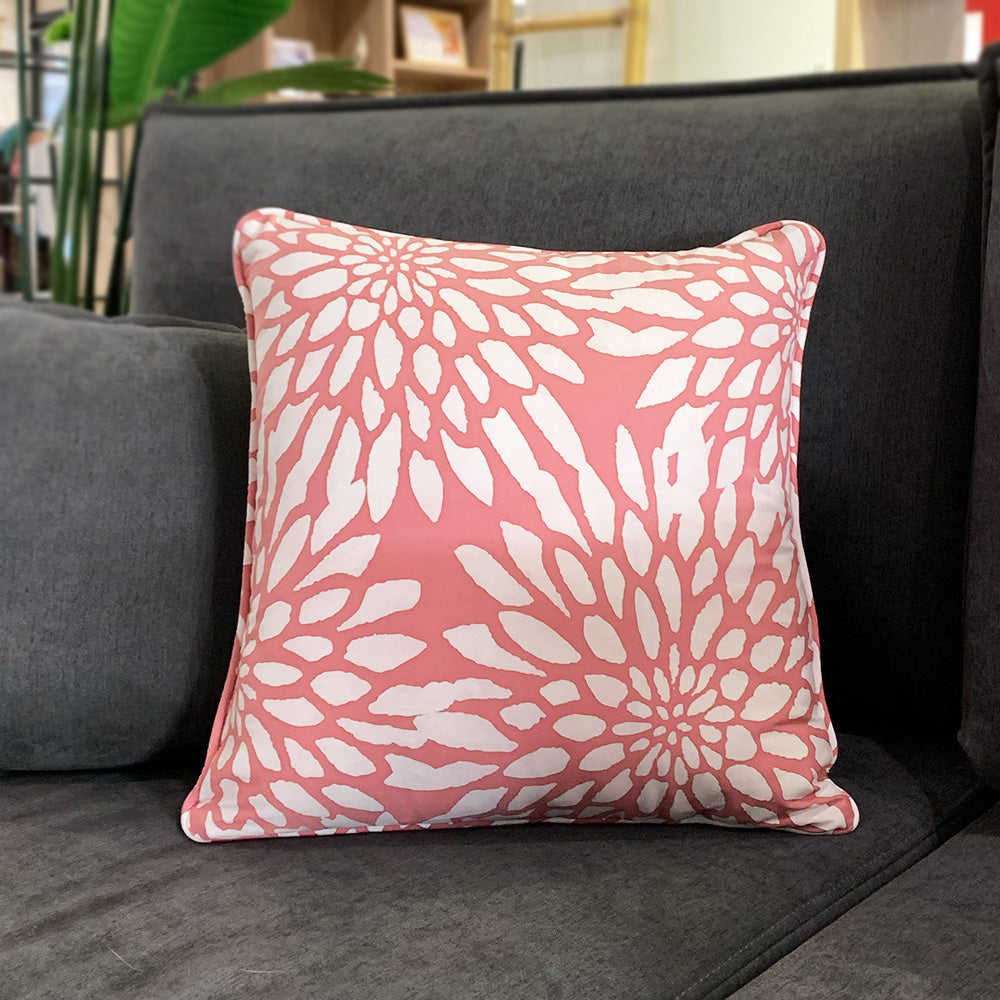 A lifestyle photo of batik pillow cover in coral bunga on a grey sofa. Made sustainably by local malaysian artisans